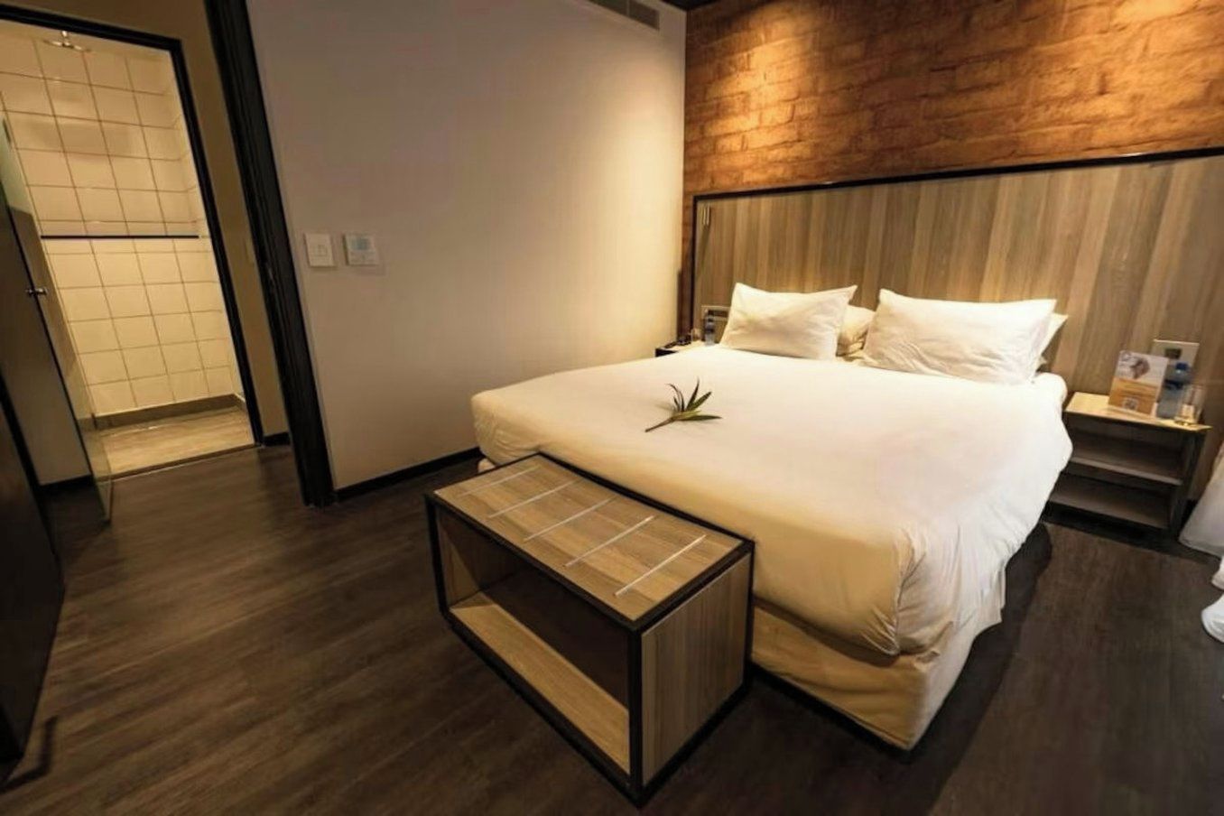 A hotel room with a large bed, a bedside table, and a small side table.