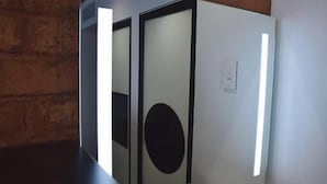 A modern, minimalist room with a glass partition, a circular black accent, and a light switch on the wall. - ONOMO Hotel Maputo (Maputo)