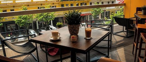 A balcony with a table, chairs, and a potted plant.