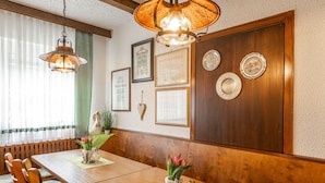 A dining area with wooden furniture, a hanging lamp, and wall-mounted plates.