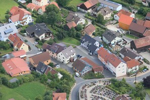 Vista aerea di una zona residenziale con case, strade e un parco circolare con aiuole fiorite.