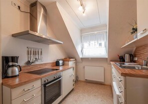 Eine Küche mit Herd, Backofen und einem Fenster mit Vorhängen.