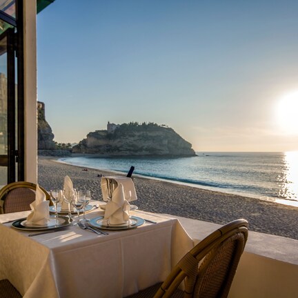 A table set for two with a view of the sea and a distant rocky outcrop.