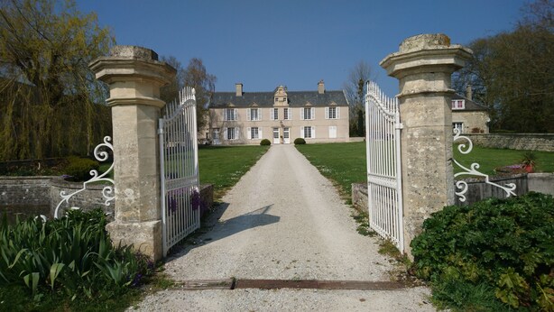 A gated entrance to a building with a gravel path leading to a large, classical-style house with multiple windows and a central door. - Manoir de Conjon (Crouay)