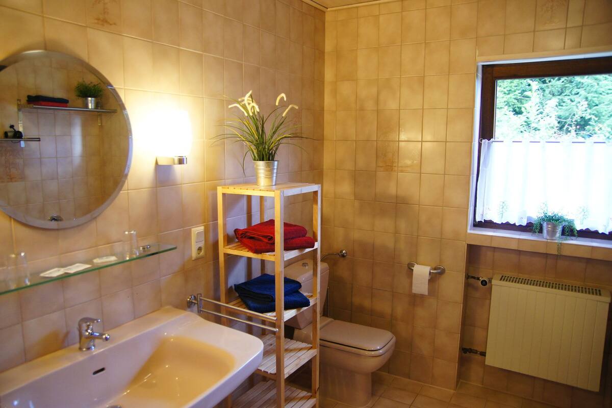 A bathroom with a bathtub, toilet, and a shelf with towels.