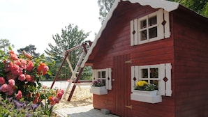 A red wooden house with white window shutters and a ladder leaning against it. - Gasthof Schumacher - Hotel garni (Freudenberg)