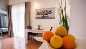 Una habitación de hotel moderna con zona de comedor, una cama y un cuadro en la pared.