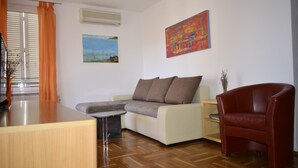 A living room with a sofa, a red armchair, a coffee table, and two paintings on the wall. - Apartment Grace (Malinska-Dubasnica)
