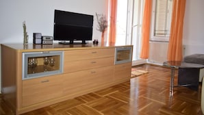 A modern living room with a wooden cabinet, a flat-screen TV, and a glass coffee table. - Apartment Grace (Malinska-Dubasnica)