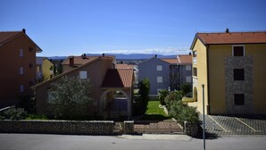 A residential area with multi-story buildings, a stone wall, and a clear blue sky. - Apartment Grace (Malinska-Dubasnica)