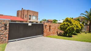 A brick building with a red roof, a gated driveway, and a sign reading "The River House 7 Emerald Cres."