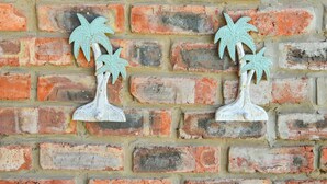 A wooden sign with palm tree decorations on a brick wall.