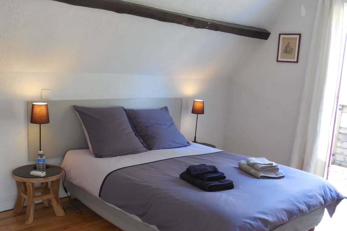 Quarto com uma cama, duas mesas de cabeceira, um abajur e um quadro na parede.