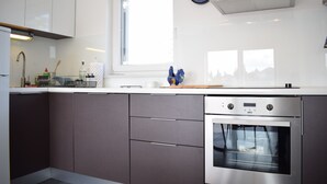 A modern kitchen with a built-in oven, a window, and a clock on the wall.