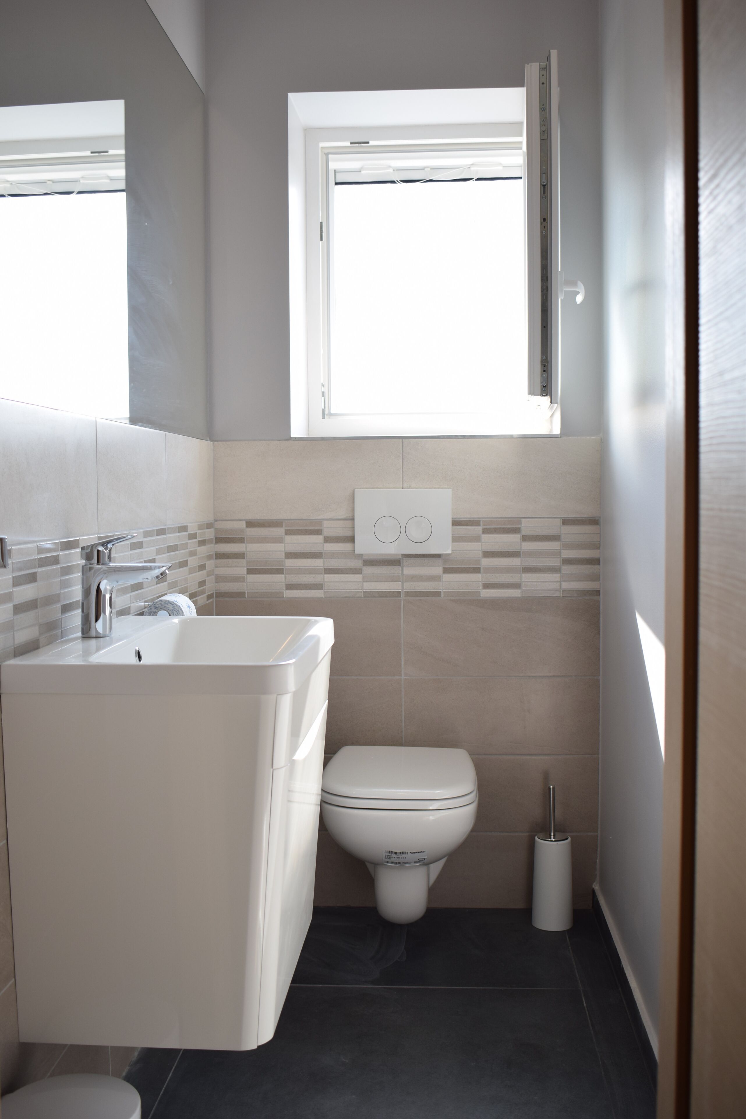 A modern bathroom with a bathtub, toilet, and window.