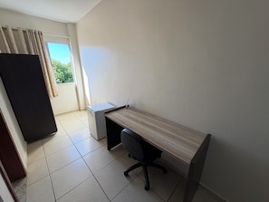 A small office space with a desk, chair, and a window with curtains. - Hotel Mundial (Pirapora)