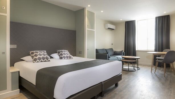 Une chambre d’hôtel moderne avec un grand lit, un canapé, une petite table et une chaise.