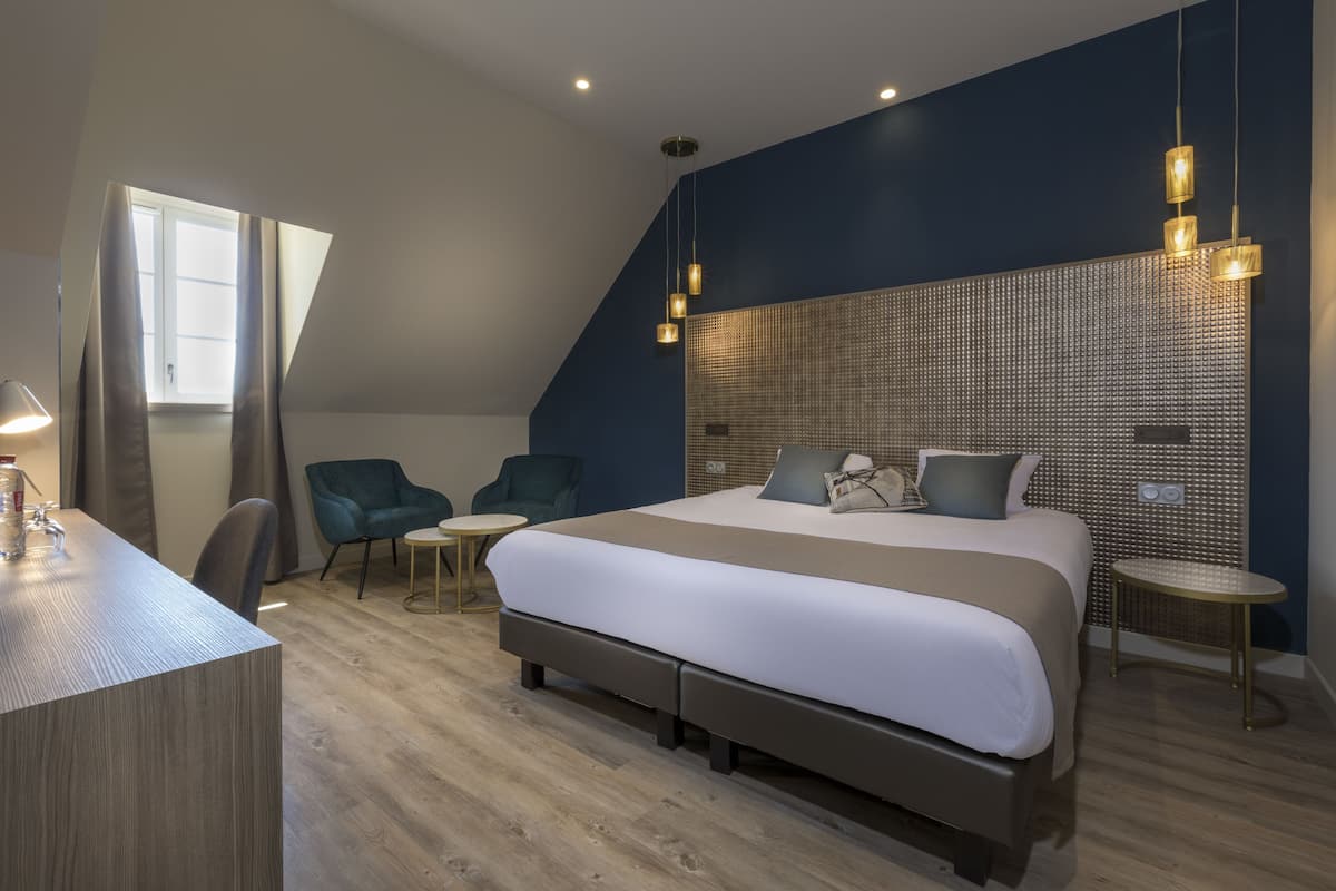 Una habitación de hotel moderna con una cama grande, un escritorio, una silla y una mesita.