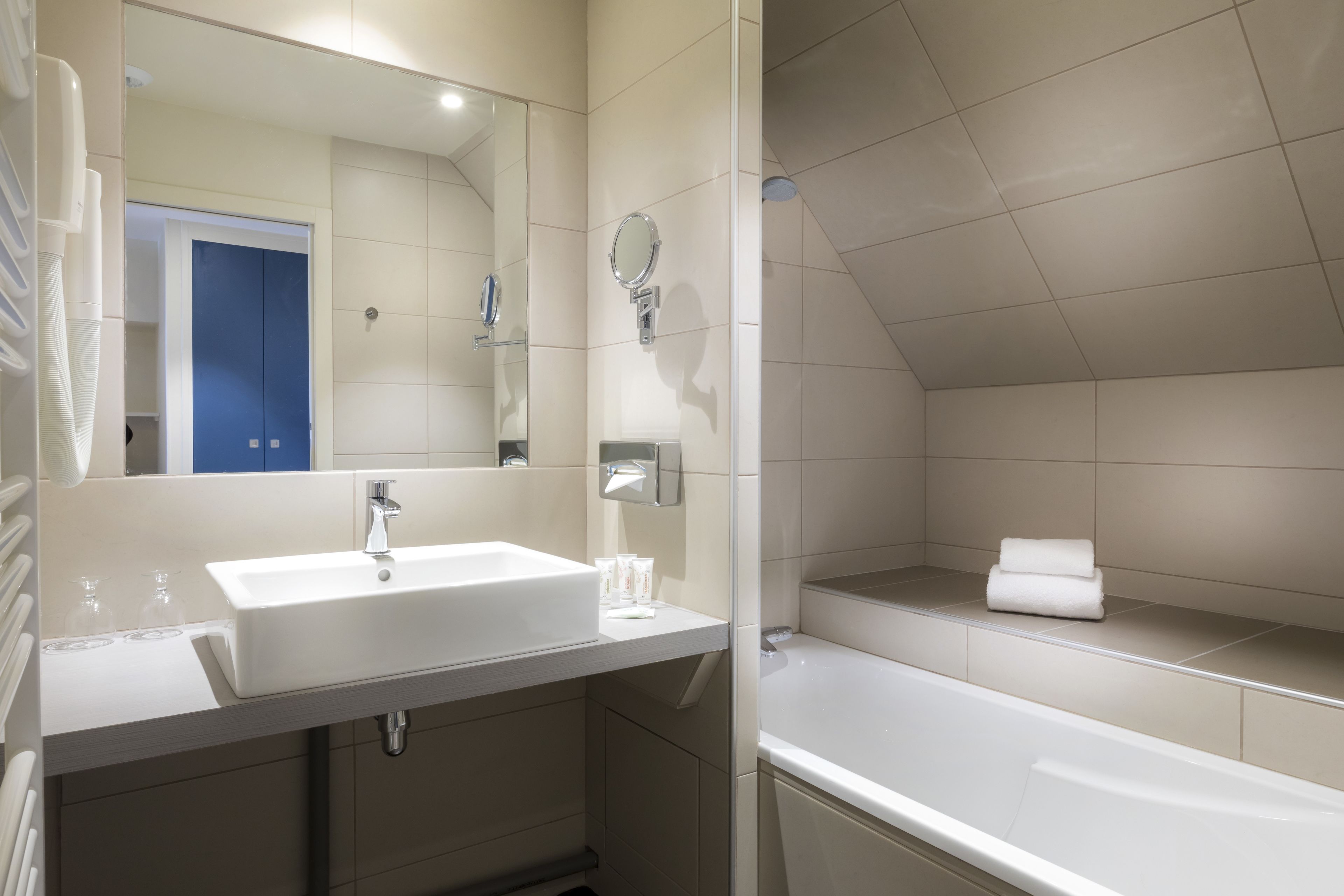 A modern bathroom with a white sink, mirror, and bathtub.