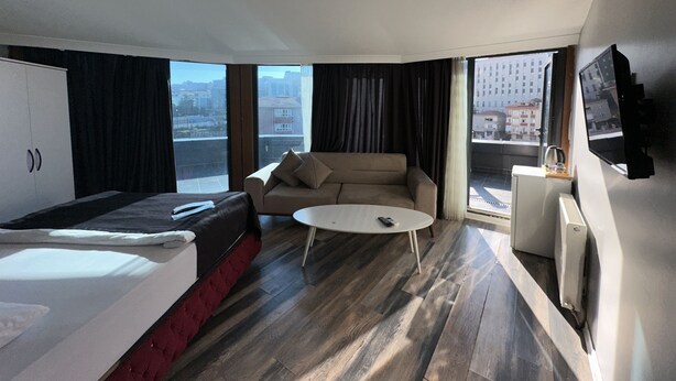 Una habitación de hotel moderna con una cama, un sofá, una mesa de café y un televisor.