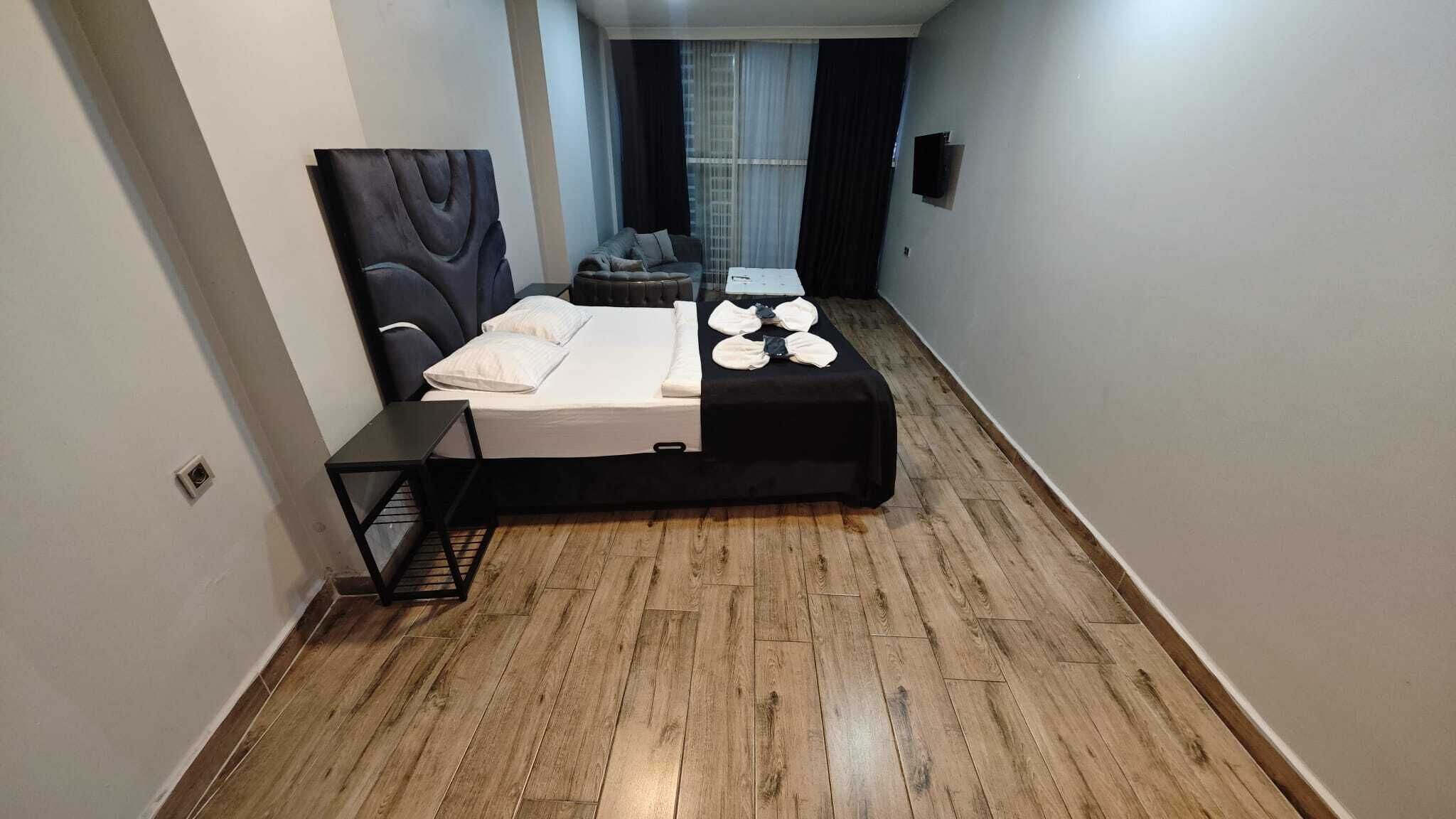 A narrow hotel room with a bed, a small table, and a chair.