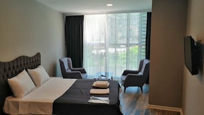 Habitación de hotel con cama, dos sillones, una mesita y televisor montado en la pared.