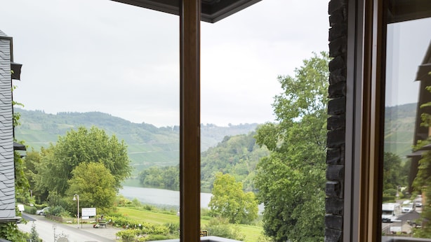 Ein hölzerner Balkon mit einer Steinmauer und Blick auf einen See und Grünflächen.
