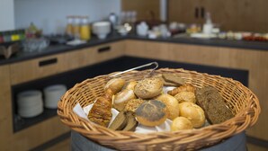 Ein Korb aus Weidengeflecht mit verschiedenen Brotsorten und Gebäck auf einer Küchenarbeitsplatte.