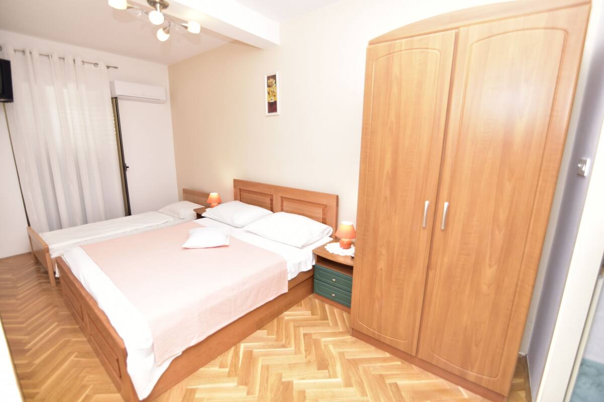 Une chambre à coucher comprenant un lit, des tables de chevet, une armoire et un appareil de climatisation.