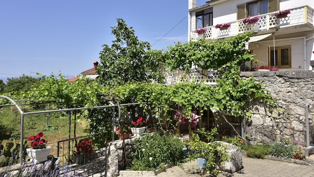Ein zweistöckiges Gebäude mit einer Steinwand und einem Balkon voller Blumen.
