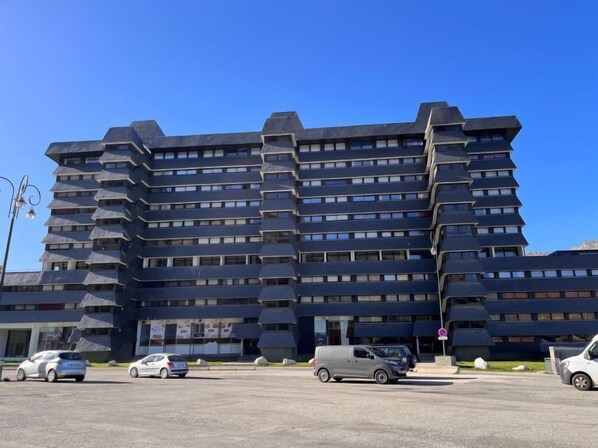 Un edificio de varias plantas con un diseño arquitectónico único, que presenta una serie de balcones escalonados y una estructura vertical destacada a la derecha.
