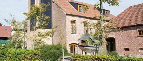 A traditional brick building with a sloped roof, a central chimney, and a small window.