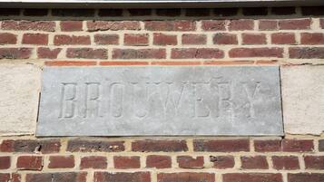 Un mur de briques sur lequel est fixée une plaque de pierre gravée du mot « BROUWERBA ».