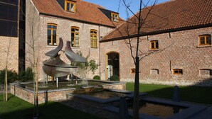 A brick building with a courtyard, a fountain, and a small pond. - Hostellerie de Biek (Aalst)