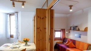 A cozy room with a dining table set for two, a sofa, and a bed.