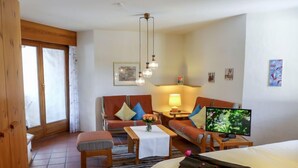 A cozy hotel room with a bed, a sofa, a small table, and a TV.