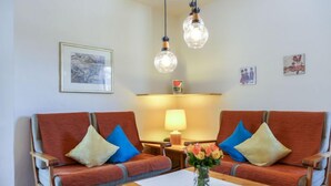 A room with two sofas, a table, and a lamp.