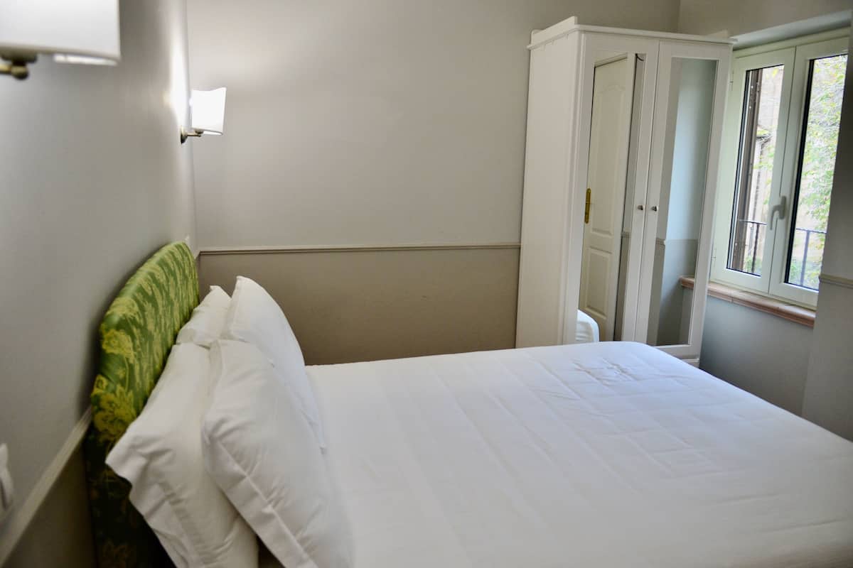 A bedroom with a bed, a window, and a wardrobe.