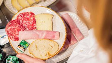 A person holding a plate with various food items.