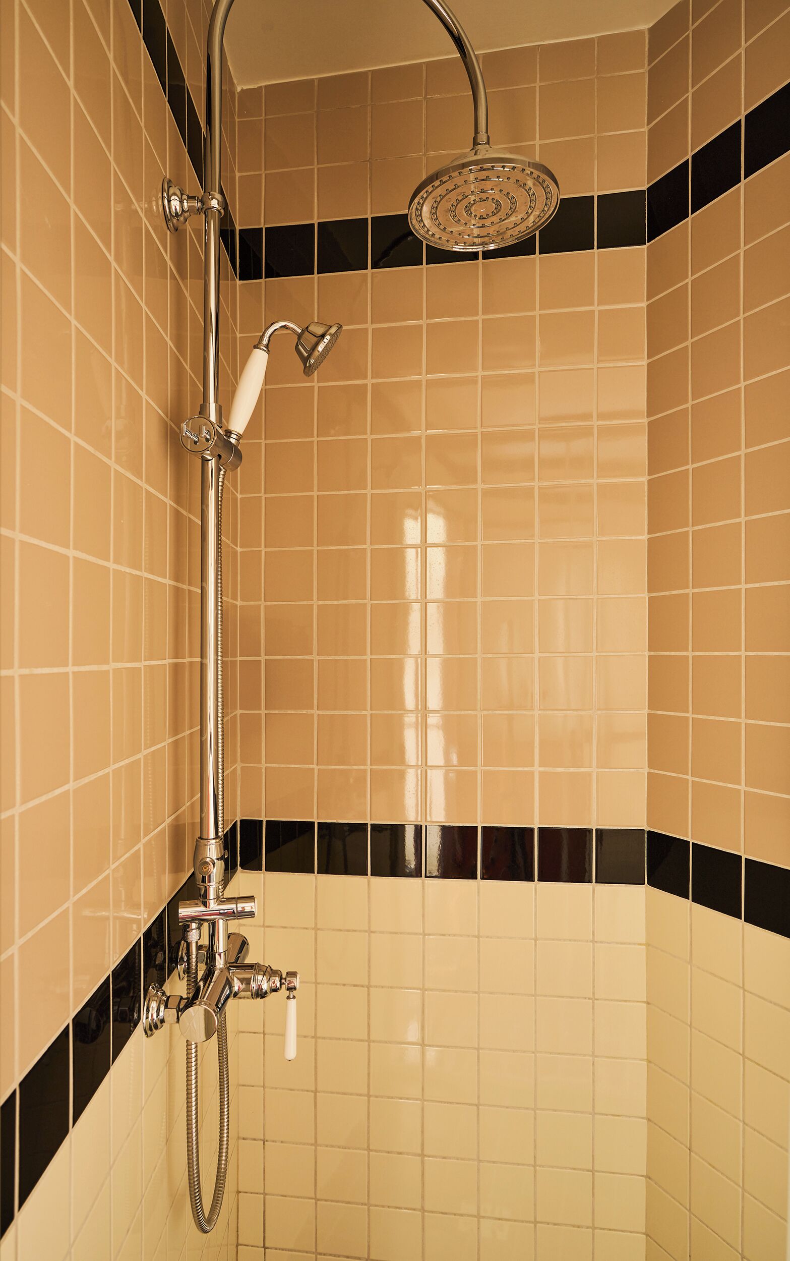 A shower with a handheld showerhead and a wall-mounted rain showerhead.