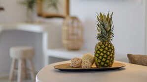 En köksbänk med en ananas, en flätad skål och ett ljus. Ovanför bänken hänger en modern pendellampa.