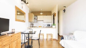 Un espace de vie compact comprenant une kitchenette, un coin repas et une chambre.