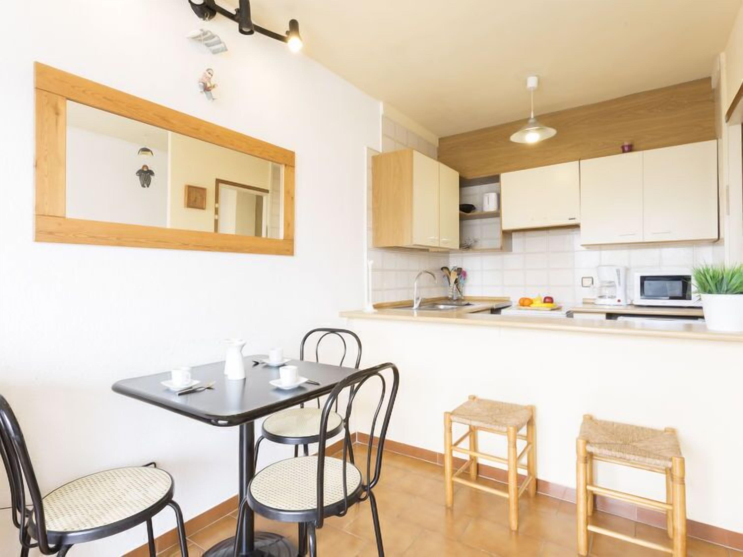 A compact kitchen with a dining area, featuring a small table, chairs, a microwave, and a sink.