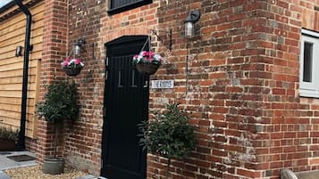 Un bâtiment en briques avec une porte noire, deux jardinières suspendues et une enseigne sur laquelle on peut lire « THE ROOMS ».