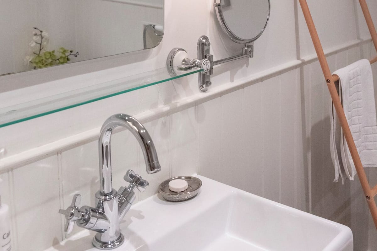 A bathroom with a white sink, a large mirror, a wall-mounted light, and a towel rack.