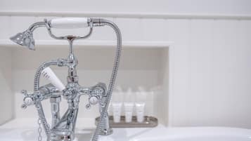 Ein Badezimmer mit chromfarbenem Wasserhahn, einer Duschbrause und einer Seifenspender.