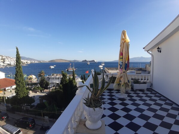 A balcony with a checkered floor, overlooking a coastal town with boats and a distant mountain. - Bistrica Hotel (Sarandë)