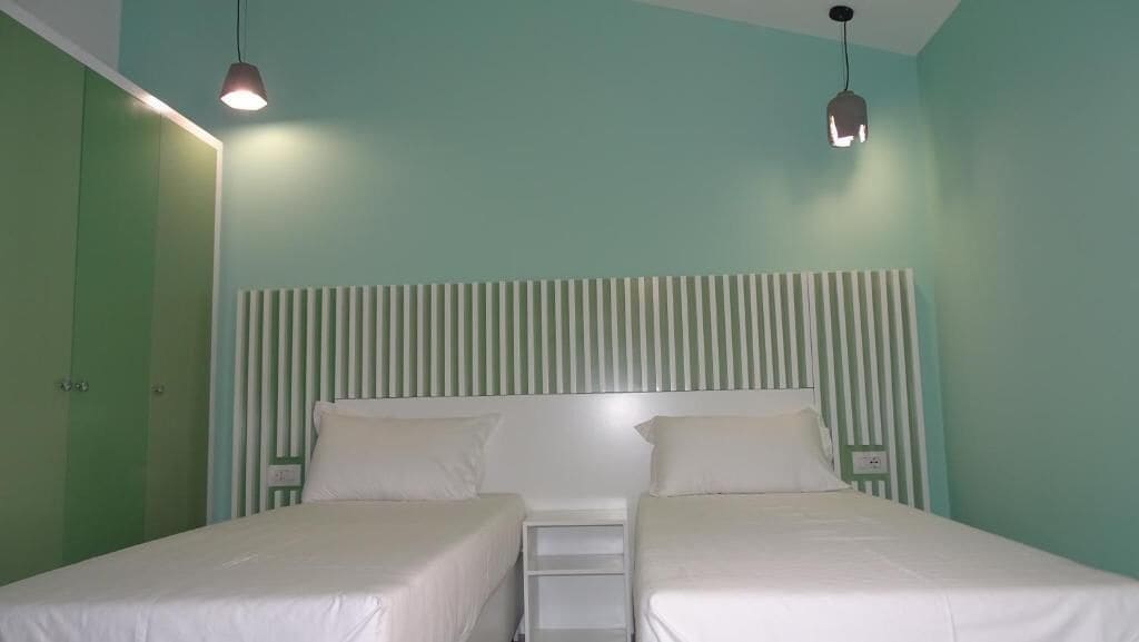 Een kamer met twee bedden, een gestreept hoofdeinde en hanglampen.
