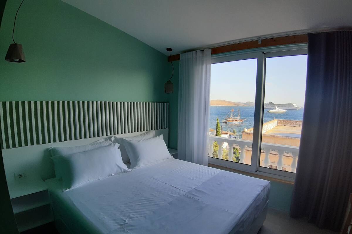 Una habitación de hotel con cama, vista al mar y balcón.