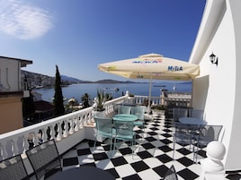 Una terraza con suelo a cuadros, mobiliario exterior y vista al mar.